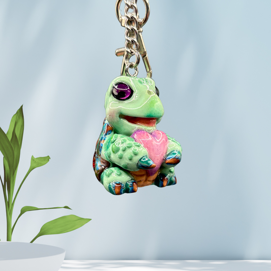 Cute baby sea turtle holding a purple heart keychain.
