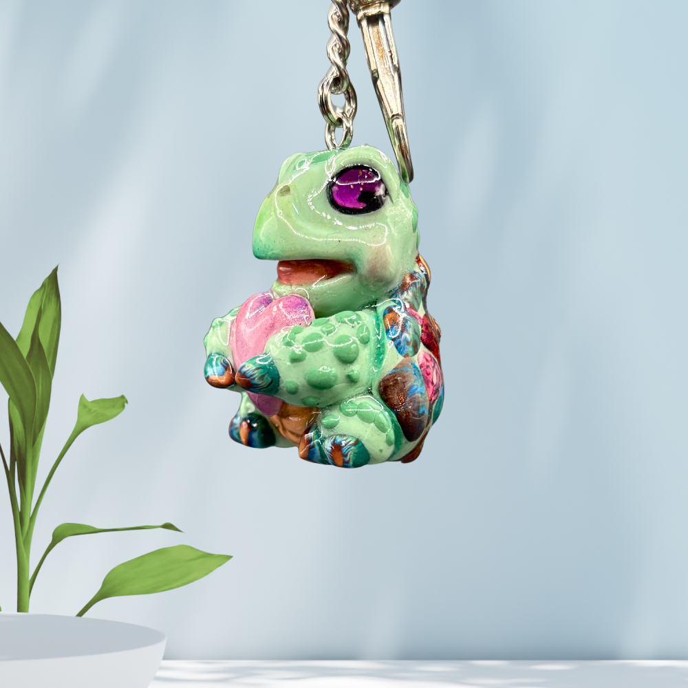 Cute baby sea turtle holding a purple heart keychain.