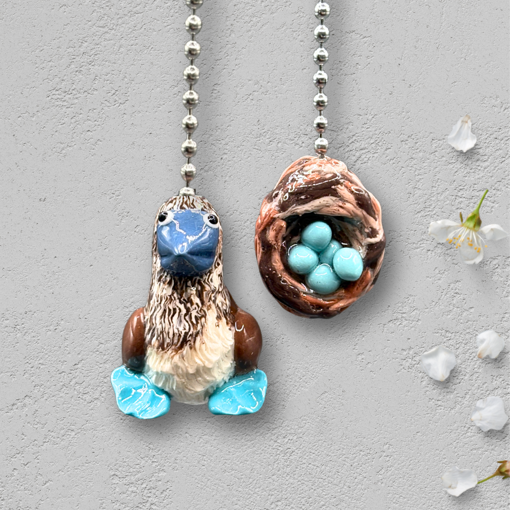 Two decorative ceiling fan pull chains with bird and nest design on a gray background.