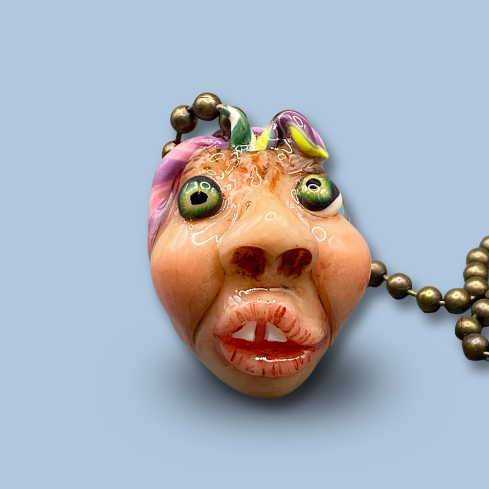 Pendant with a face design on a light blue background