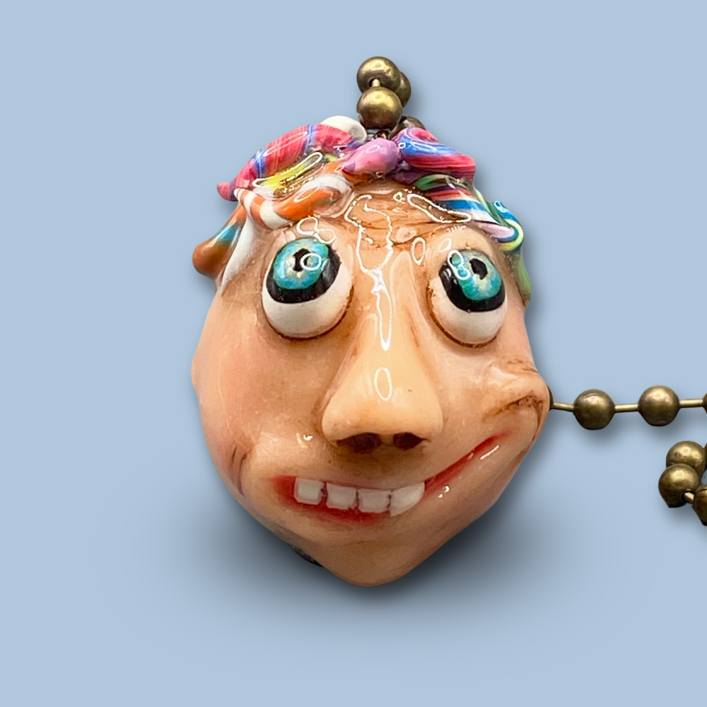 Pendant with a face design on a light blue background