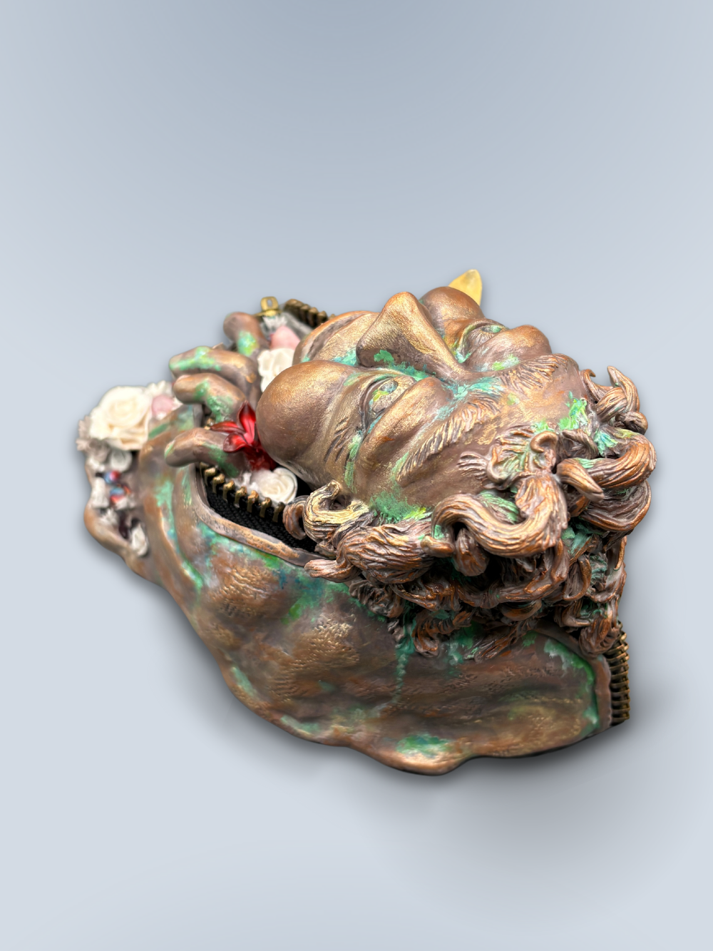 Hand made sculpture using Polymer clay, depicting a happy face exiting from a giant suit. This sculpture is painted to look like patinaed bronze and is decorated with natural stone, gems and sculpted flowers.
