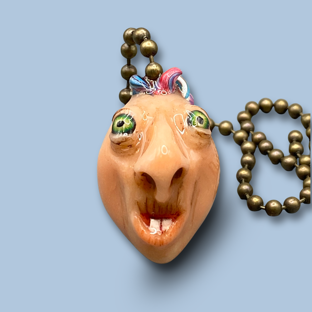 Pendant with a face design on a light blue background