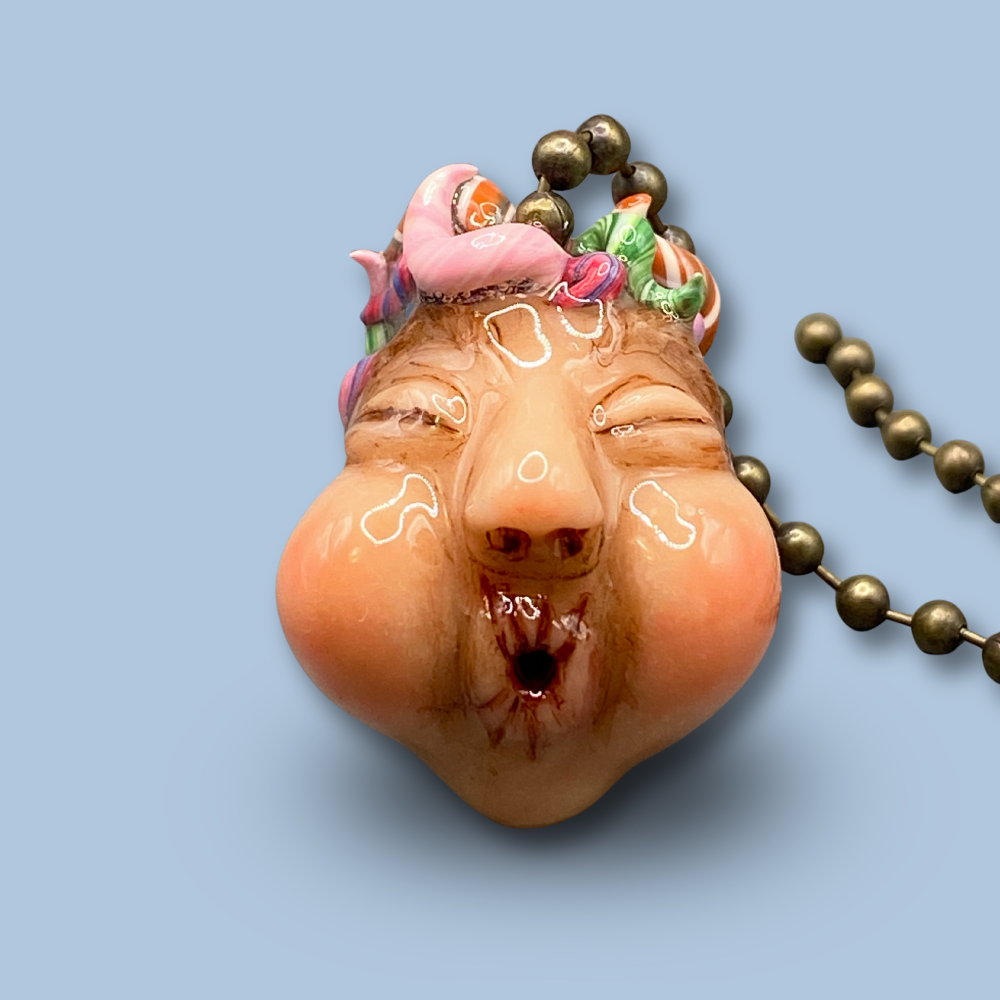 Pendant with a face design on a light blue background