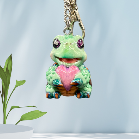 Cute baby sea turtle holding a purple heart keychain.