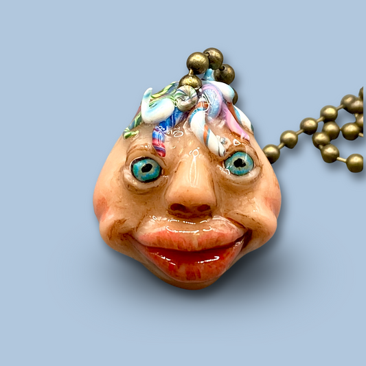Pendant with a face design on a light blue background