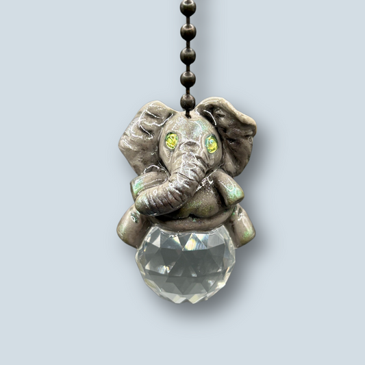 African Elephant light pull with crystal ball. Handmade with polymer clay. Elephant is Grey colored with silver and metallic green sheen sitting on a clear crystal ball 