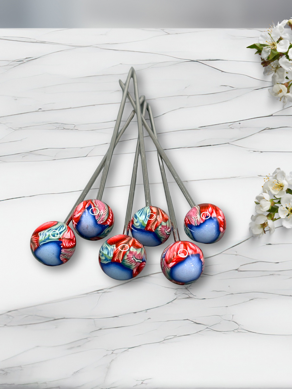 Set of colorful clay cocktail picks on a marble surface with flowers.