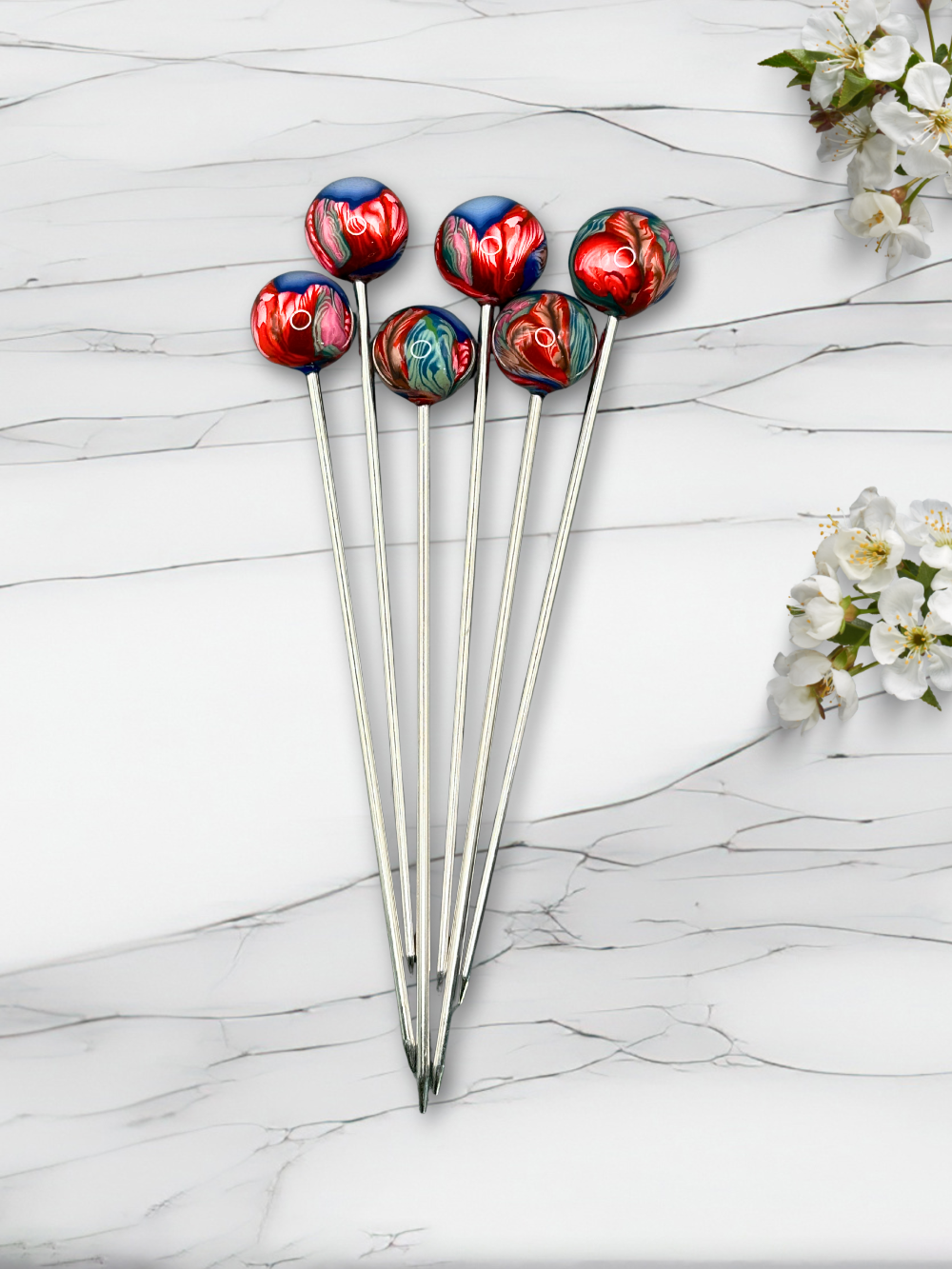 Set of colorful clay cocktail picks on a marble surface with flowers.