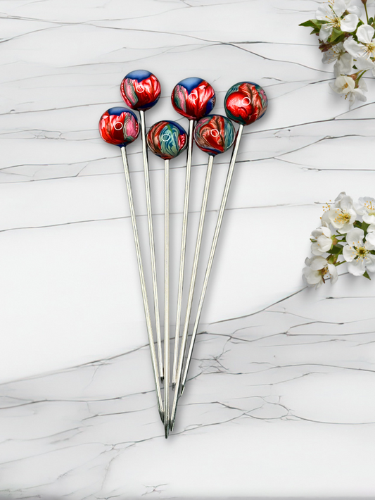 Set of colorful clay cocktail picks on a marble surface with flowers.