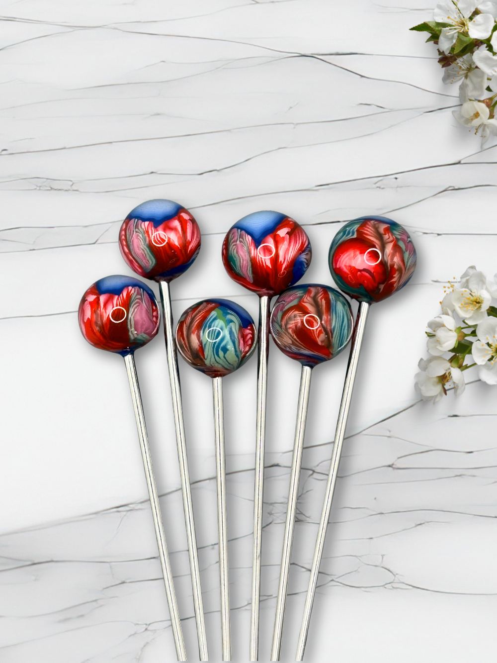 Set of colorful clay cocktail picks on a marble surface with flowers.
