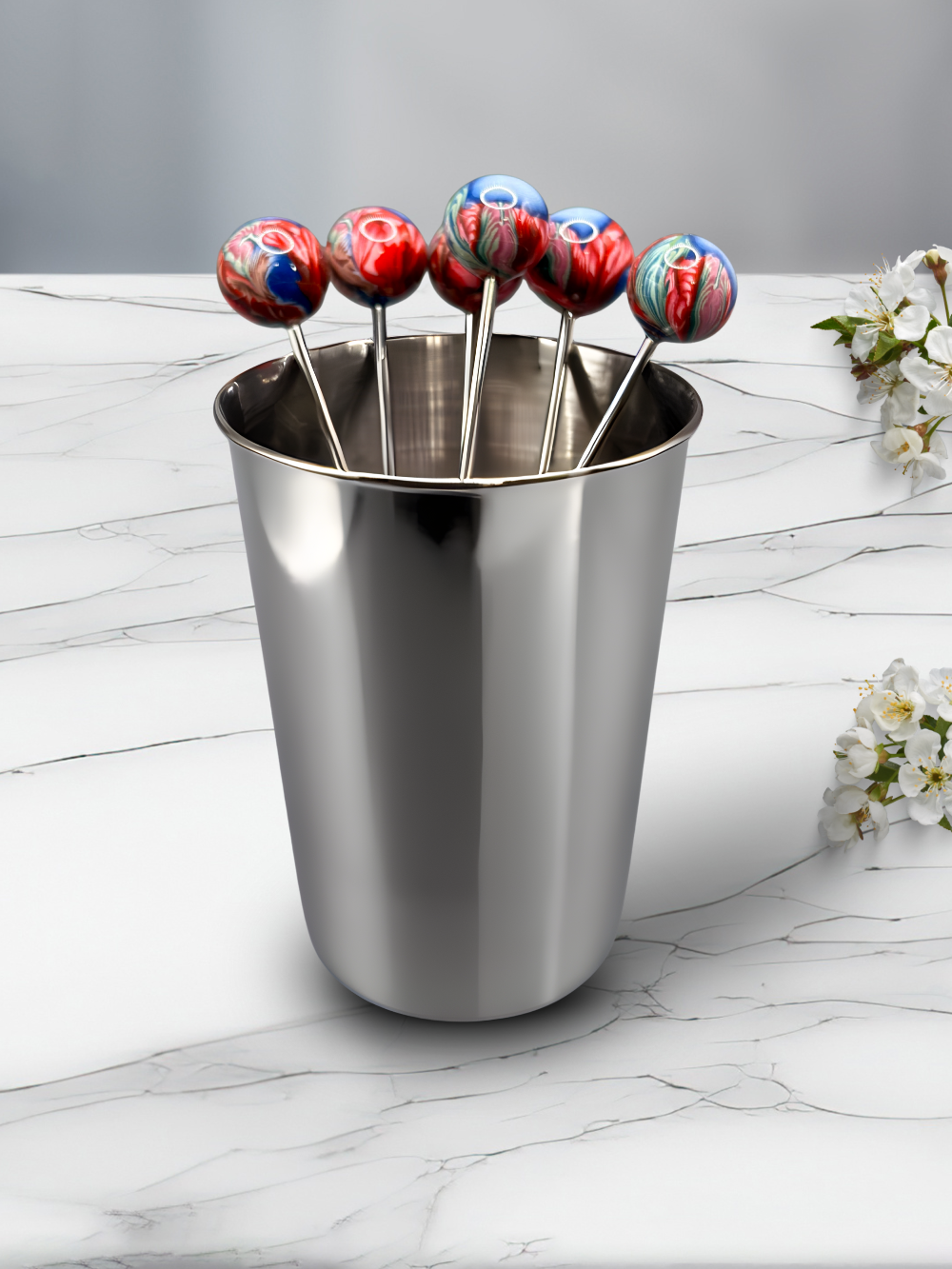Set of colorful clay cocktail picks on a marble surface with flowers.