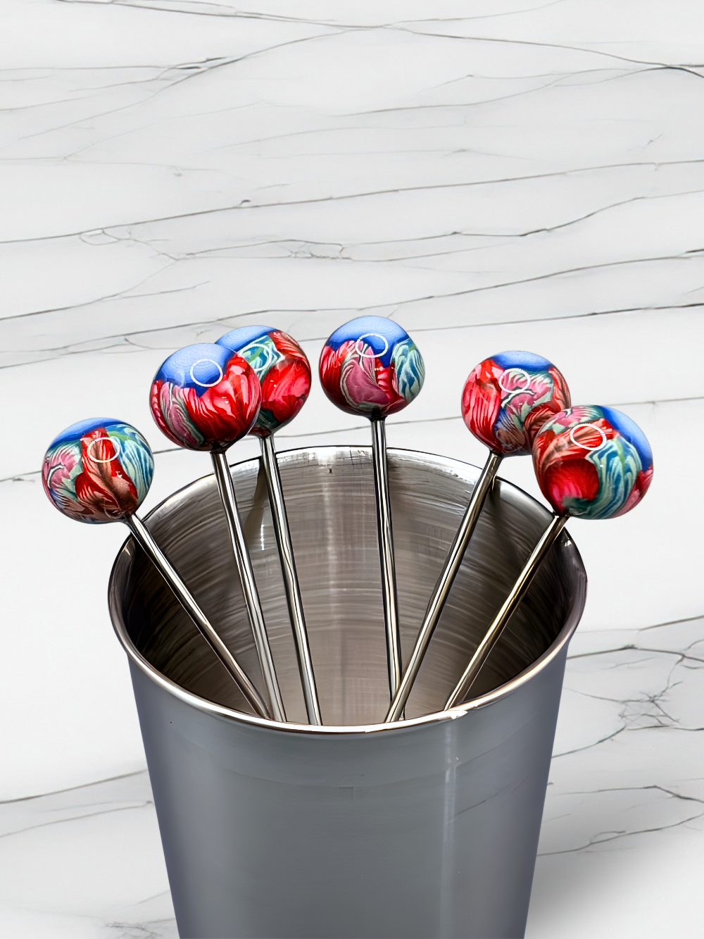 Set of colorful clay cocktail picks on a marble surface with flowers.