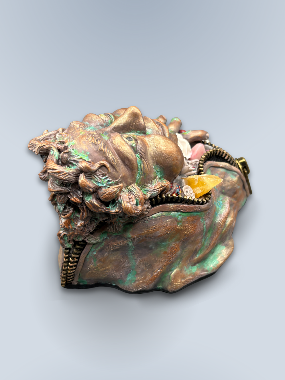 Hand made sculpture using Polymer clay, depicting a happy face exiting from a giant suit. This sculpture is painted to look like patinaed bronze and is decorated with natural stone, gems and sculpted flowers. 