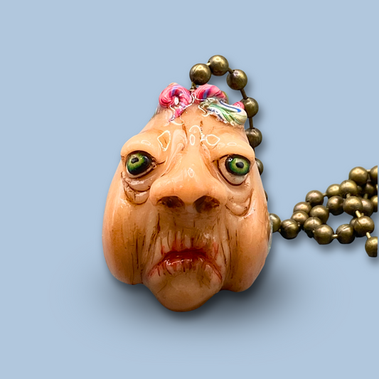 Pendant with a face design on a light blue background
