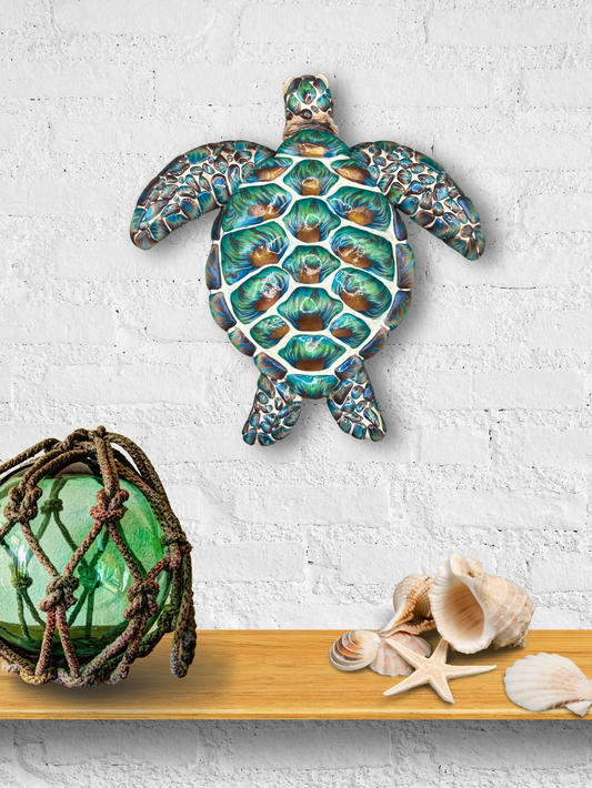 Decorative turtle wall art on a textured white wall with a green glass ball and shells below.