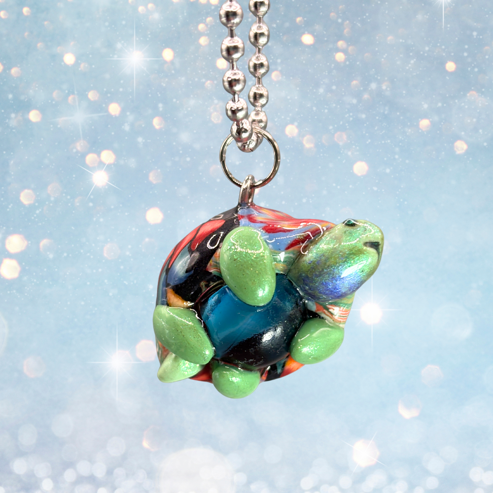 Green and red turtle car charm with a blue marble in its belly